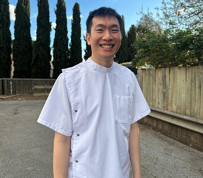 Dr Anthony Lim, principal dentist at Strathalbyn Family Dental, smiling outdoors in his dental uniform